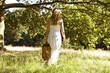 A young woman carrying a picnic basket, rear view