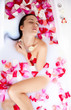 Attractive naked girl enjoys a bath with milk and rose petals