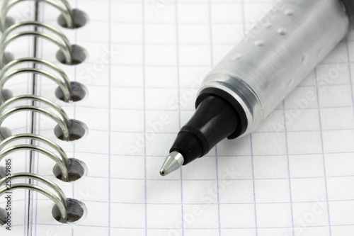 stylo gel noir à bille sur page quadrillée de carnet à spirale