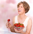 Smiling woman in good mood eating strawberries