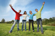 Group of four happy friends together outdoors on green field