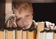 The boy at a bookcase gets the book.