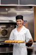 Smiling young baker with baguettes Smiling young baker with baguettes