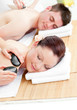 Lovely young couple receiving a back massage with hot stones Lovely young couple receiving a back massage with hot stones