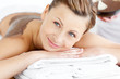 Portrait of a radiant woman lying on a massage table with mud on