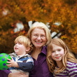 glückliche Oma mit ihren beiden Enkelkindern im Herbst