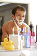 Reflection of young man shaving in mirror