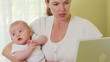 Mother working on laptop with baby