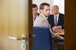Businessmen in meeting while one looking at door