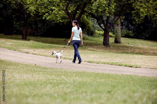 Photo: A young woman walking her dog in the park A young woman walking her dog in the park