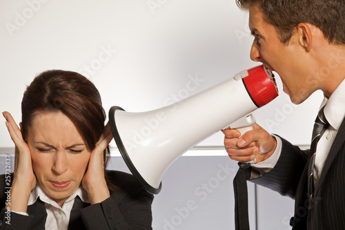 Photo: Businesswoman shouting at businessman through megaphone Businesswoman shouting at businessman through megaphone