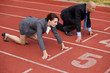 Businessman and woman on start line of running track
