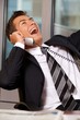 Businessman using telephone in office, smiling