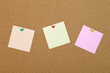 Three note papers attached to cork board with pins.