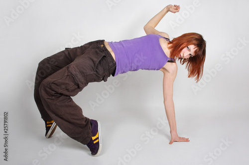 young redhead girl in hip-hop clothes in dance position, standin