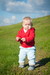 adorable baby walking through green road  within red jacket with