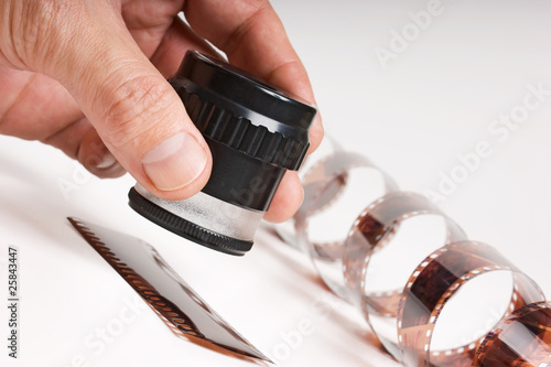 Photo: hand holding magnifying glass and film hand holding magnifying glass and film