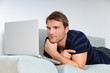 Young man relaxing with laptop on a couch