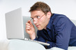 Young man relaxing with laptop on a couch and thinking