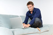 Foto: Young man relaxing with laptop on a couch Young man relaxing with laptop on a couch