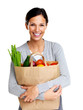 Pretty woman holding a grocery bag and smiling on white