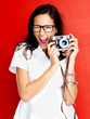 Happy young woman winking with a camera in hand Happy young woman winking with a camera in hand