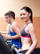 Cute athletic woman standing on a running machine with earphones