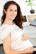 Pregnant businesswoman smiling at the camera sitting at her desk