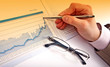 Businessman's hand showing diagram on financial report with pen.