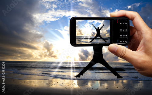 Photo: Camera mobile phone and happy jumping man Camera mobile phone and happy jumping man