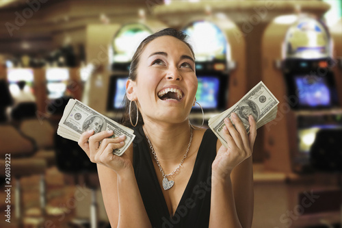 Photo: Glamorous mixed race woman in casino holding 100 dollar bills Glamorous mixed race woman in casino holding 100 dollar bills
