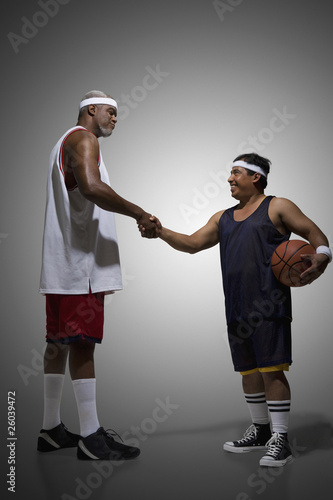 Photo: Tall basketball player shaking hands with short basketball player Tall basketball player shaking hands with short basketball player