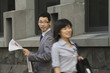 Korean businessman with newspaper watching woman walking