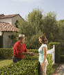 Hispanic man and woman shaking hands over hedge