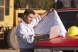 Hispanic male contractor looking at map and laptop