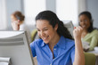 Hispanic businesswoman cheering at desk