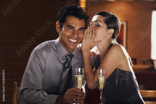 Photo: Hispanic couple drinking champagne and telling secrets Hispanic couple drinking champagne and telling secrets