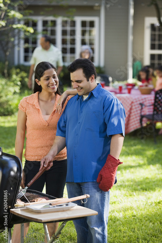 Photo: Hispanic couple grilling in backyard Hispanic couple grilling in backyard