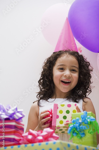 Photo: Hispanic girl opening gift at birthday party Hispanic girl opening gift at birthday party