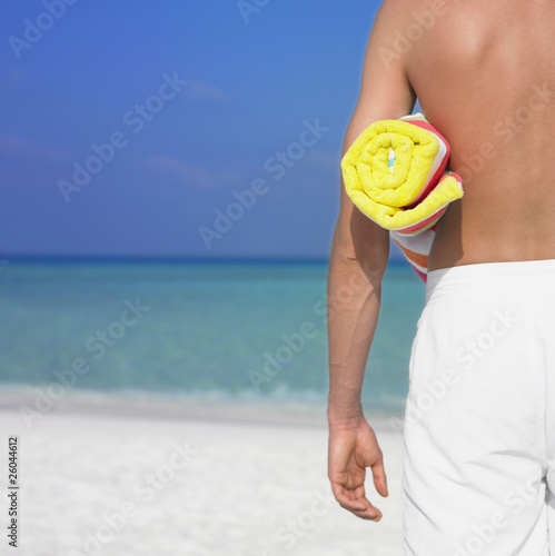 Photo: Man holding towel at beach Man holding towel at beach