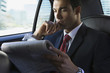 Hispanic businessman reading newspaper in limousine