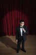 Asian man in tuxedo holding microphone onstage