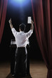 Asian man standing at podium with arms raised