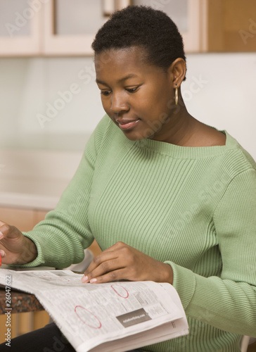 Photo: African woman looking at classified ads African woman looking at classified ads