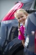 Schülerin blickt zwischen Autos hervor