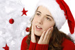 Beautiful young woman wearing santa hat next to christmas tree o
