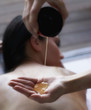 Masseuse pouring massage oil into hand