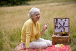 A senior woman having a picnic, holding a glass of champagne