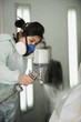 Hispanic worker painting car in auto body shop
