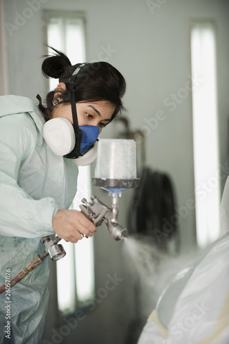 Photo: Hispanic worker painting car in auto body shop Hispanic worker painting car in auto body shop